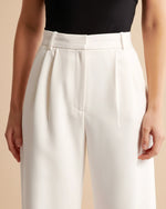 White pants worn by a person on a beige background