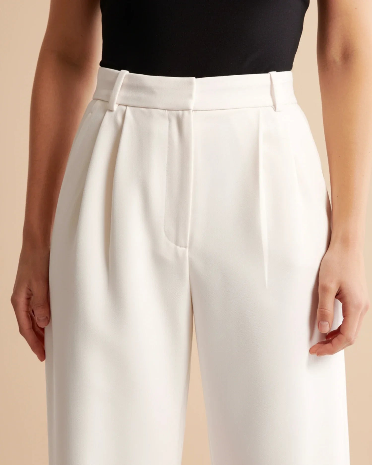 White pants worn by a person on a beige background