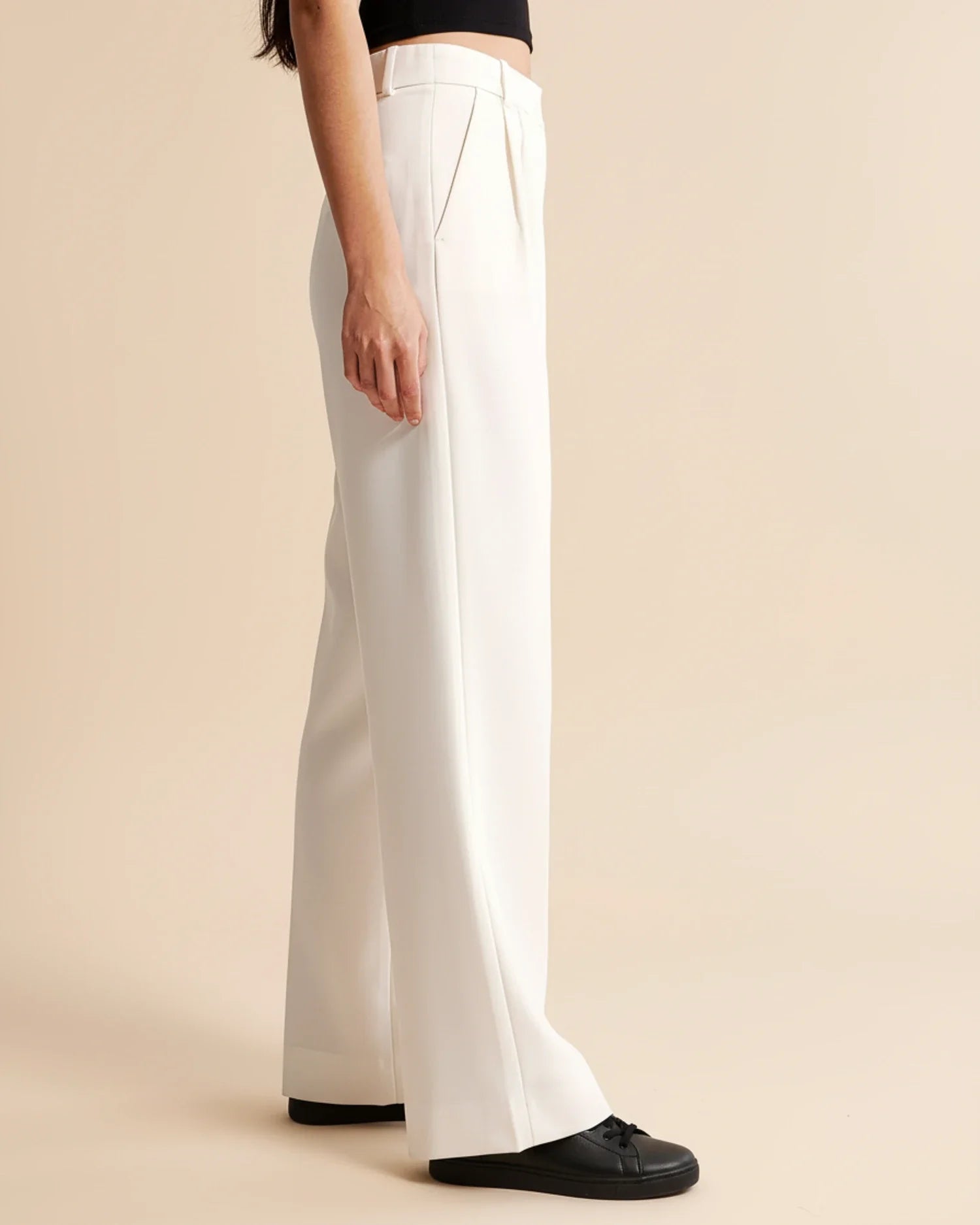 White pants worn by a person on a beige background