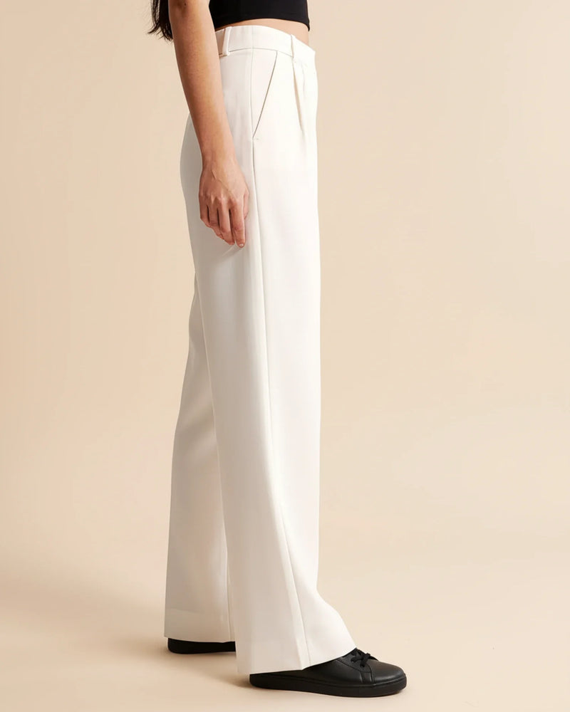 White pants worn by a person on a beige background
