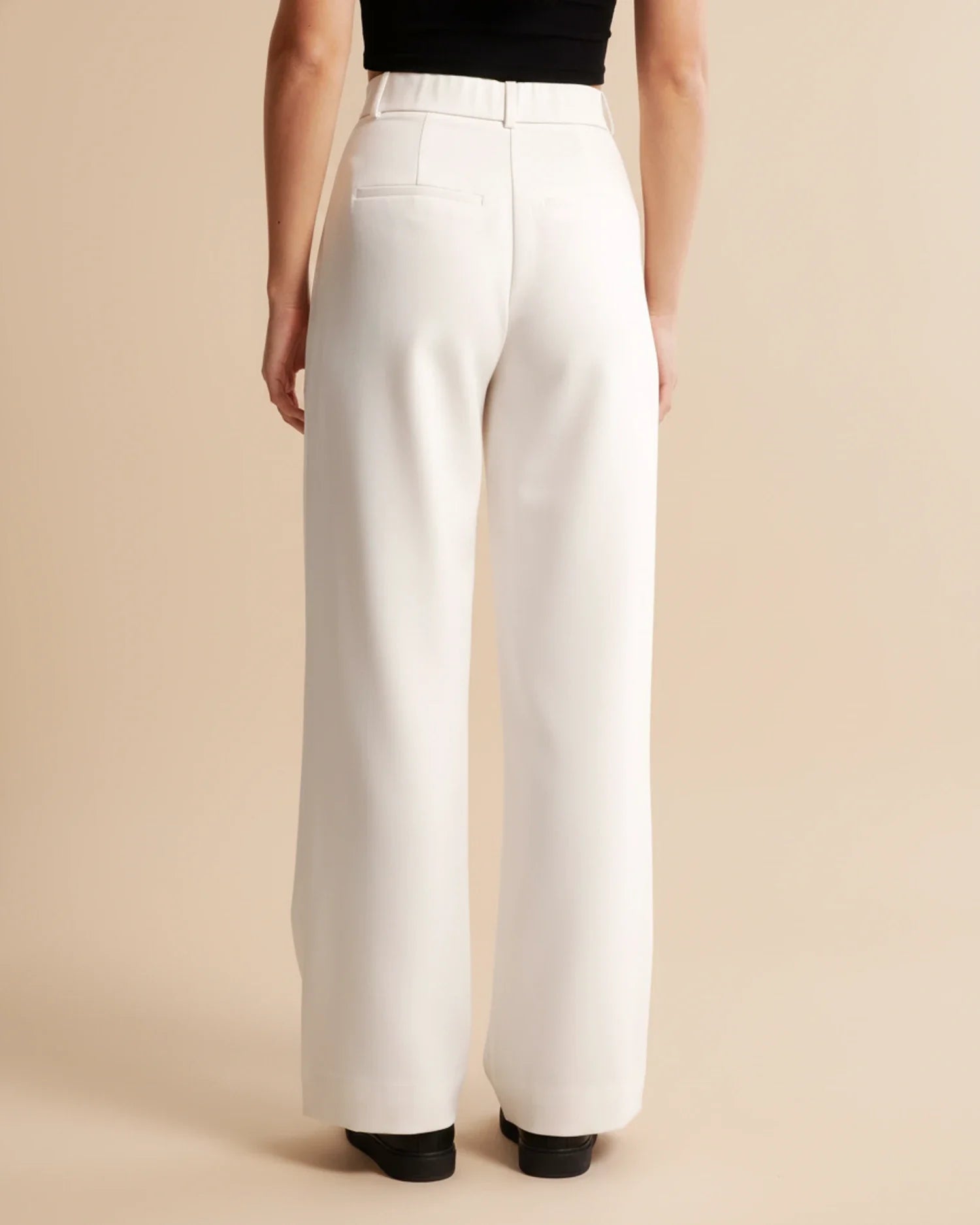 White wide-leg pants worn by a person on a beige background