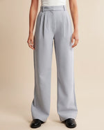 Person wearing light gray wide-leg pants on a beige background