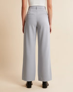 Person wearing light gray wide-leg pants on a beige background