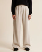 Person wearing beige wide-leg pants and a black top on a plain background