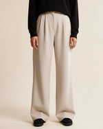 Person wearing beige wide-leg pants and a black top on a plain background