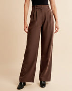 Brown wide-leg pants worn by a person on a beige background