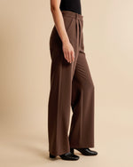 Brown wide-leg pants worn by a person on a beige background