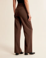 Brown wide-leg pants worn by a person on a beige background