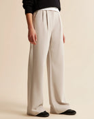 Person wearing beige wide-leg pants on a beige background