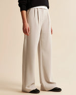 Person wearing beige wide-leg pants on a beige background