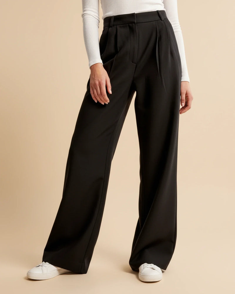 Person wearing black wide-leg pants on a beige background