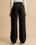 Black wide-leg pants worn by a person on a beige background
