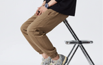Person wearing brown pants and gray sneakers on a white background