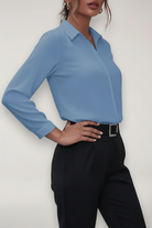 Person wearing a light blue shirt and black pants against a white background