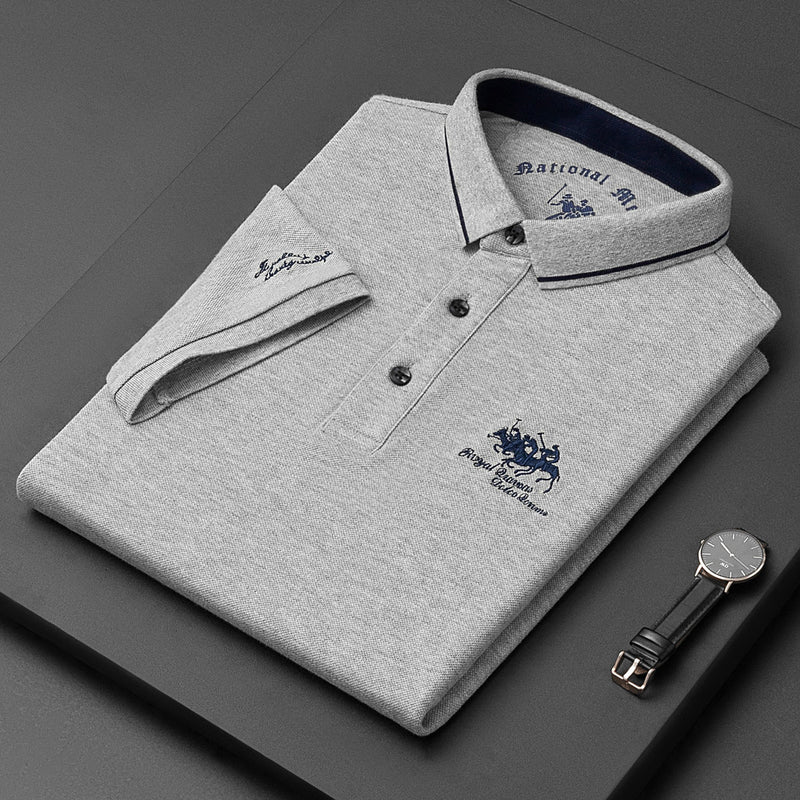 Folded gray polo shirt with brand logo on a dark surface