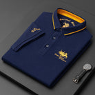 Folded navy blue polo shirt with yellow accents and branding on a dark surface.