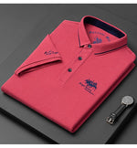 Folded red polo shirt with brand logo on a dark surface, next to a watch.