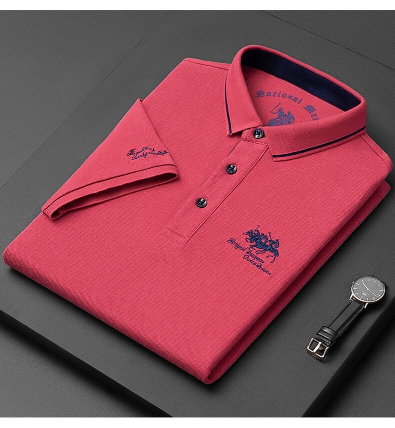 Folded red polo shirt with brand logo on a dark surface, next to a watch.