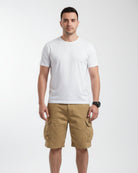 Person wearing beige cargo shorts with a blurred background