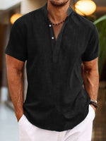 Man wearing a black short-sleeve shirt and white pants in an outdoor setting