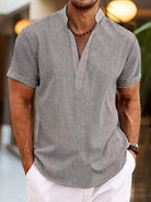 Man wearing a gray short-sleeve shirt with a blurred background