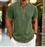 Man wearing a green patterned shirt and white pants in an outdoor setting