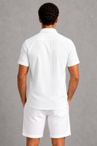 Person wearing a white striped shirt and shorts against a gray background