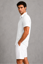 Man wearing a white dress shirt and shorts against a gray background