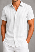 Man wearing a white short-sleeve button-up shirt against a gray background