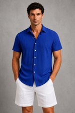 Man wearing a blue shirt and white shorts against a gray background