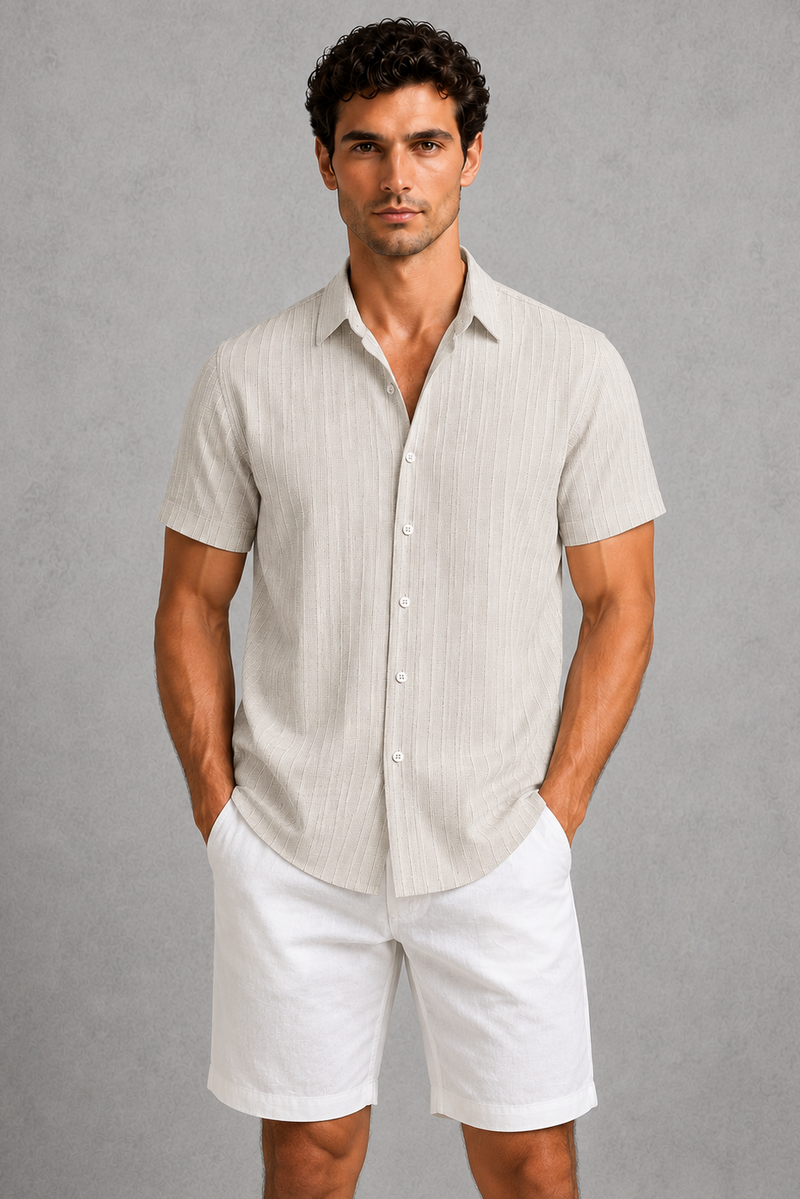 Man wearing a light-colored shirt and white shorts against a gray background
