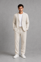 Man wearing a beige suit with white sneakers on a gray background