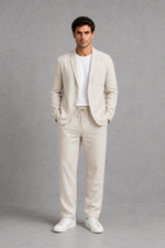 Man wearing a beige suit with white sneakers on a gray background