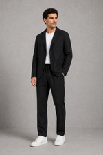 Man wearing a black suit with white sneakers on a gray background