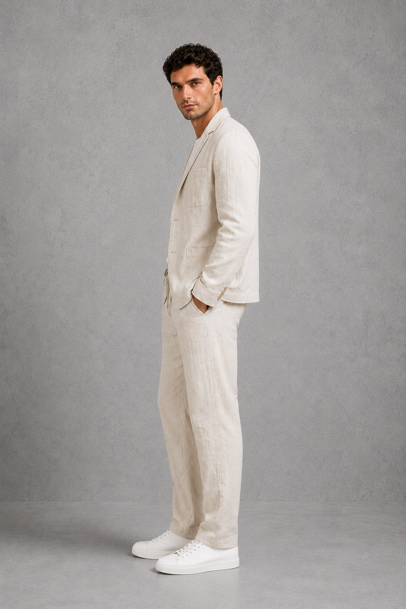 Man wearing a beige suit and white sneakers against a gray background