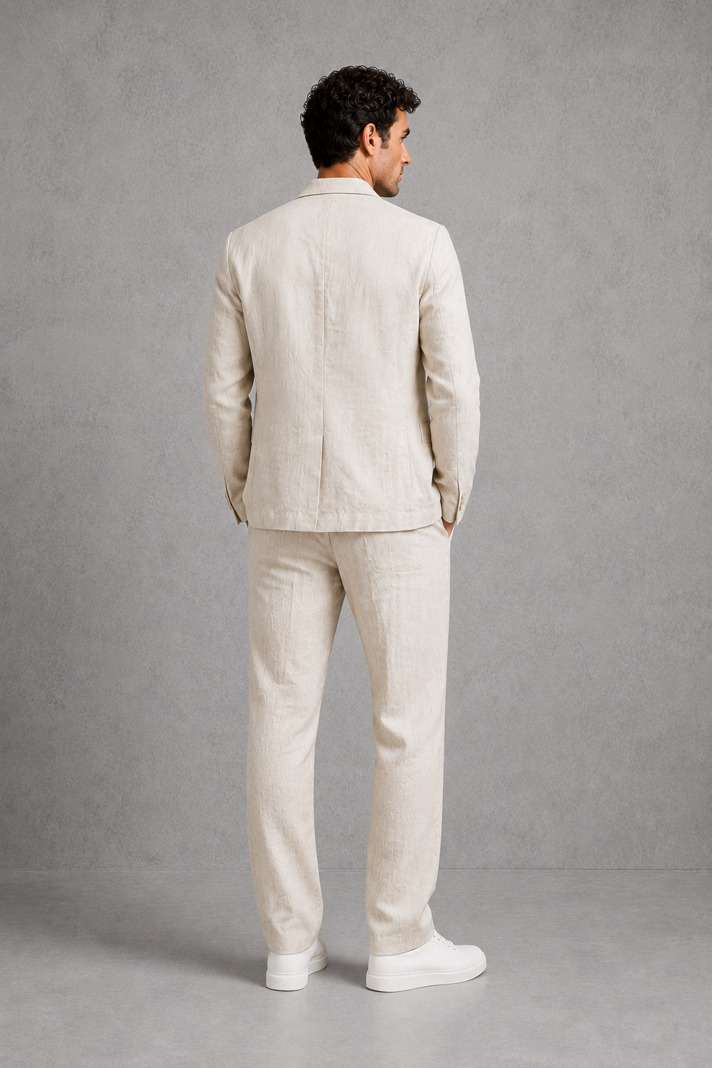 Man wearing a beige suit standing against a gray background