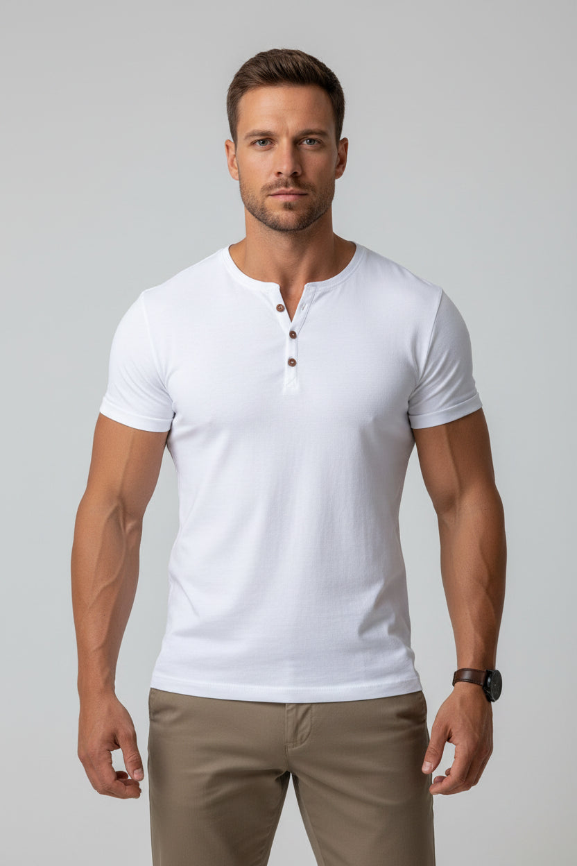 Man wearing a white V-neck t-shirt and brown pants outdoors.