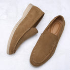 Pair of brown suede loafers on a white textured background