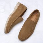 Pair of brown suede loafers on a white textured background
