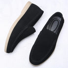 Black loafers with beige soles on a white background