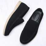Black loafers with beige soles on a white background