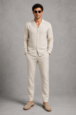Man wearing a beige linen suit against a gray background