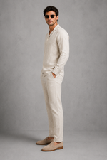 Man wearing a beige linen suit with sunglasses against a gray background