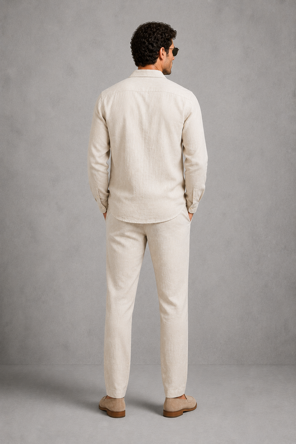 Man wearing a beige linen suit standing against a gray background