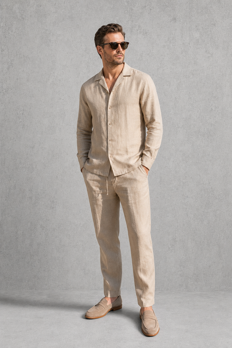 Man wearing a beige linen suit with sunglasses against a gray background