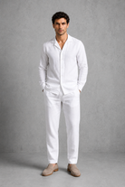 Man wearing a white linen suit against a gray background