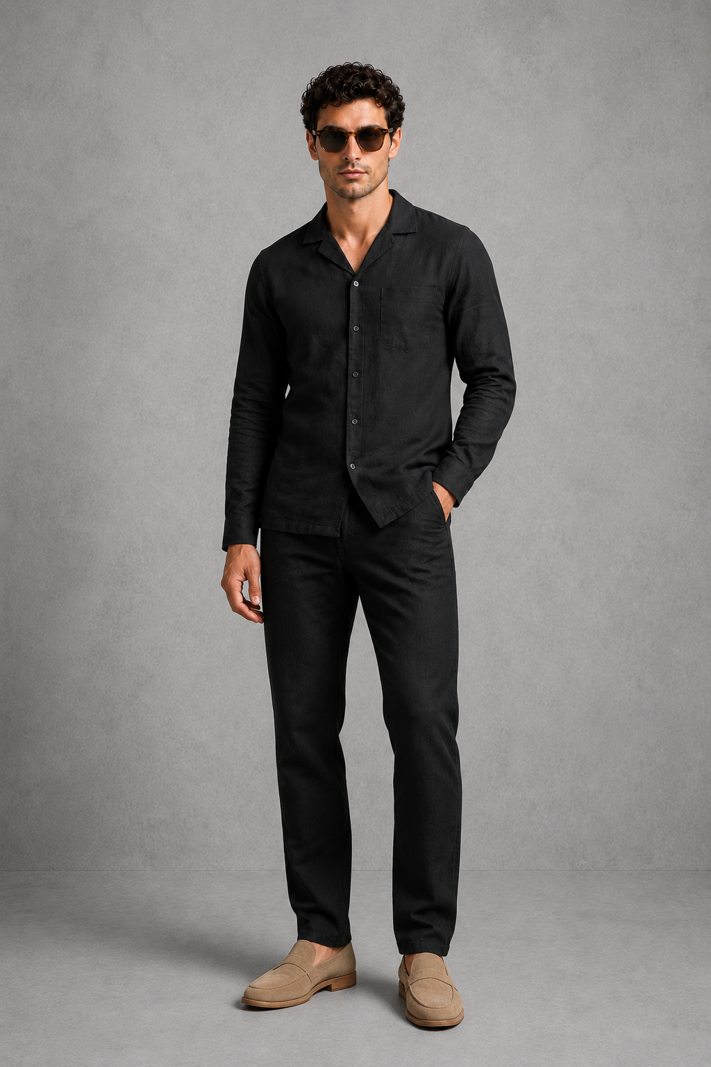 Man wearing a black shirt and pants with beige shoes on a gray background