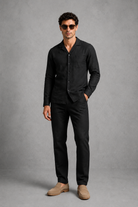 Man wearing a black shirt and pants with beige shoes on a gray background