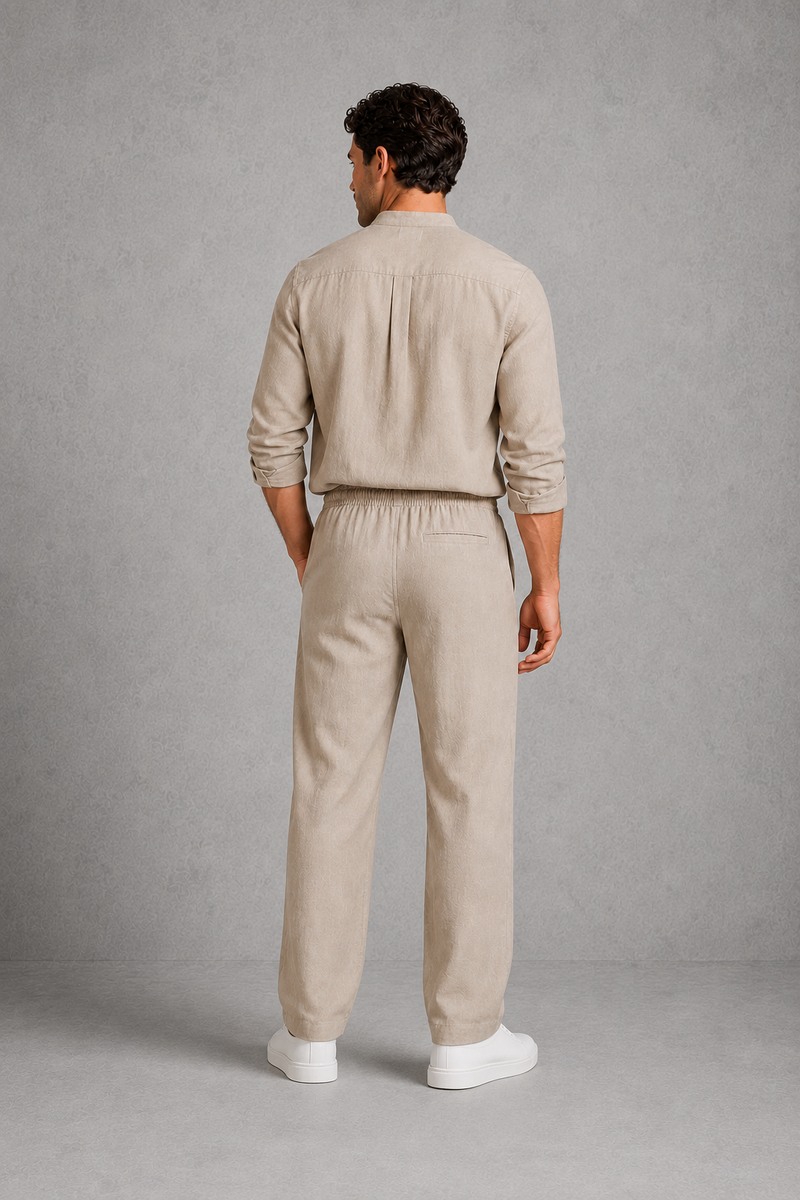 Man wearing a beige outfit standing against a gray background