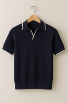 Navy short-sleeve sweater with white trim on a wooden hanger against a beige background